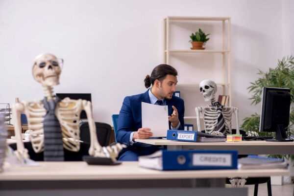 A young male employee with skeletons in the office.