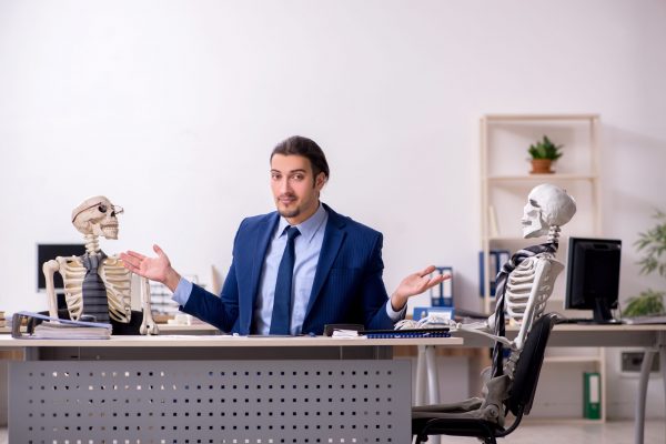 Young male employee with skeletons in the office.